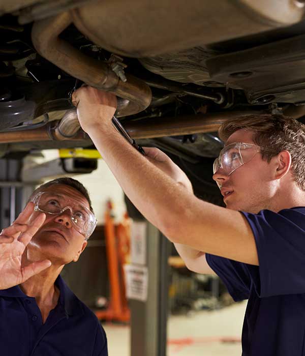 two men servicing underneath of car